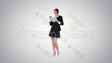 穿裙子跳舞的可爱女人，在<strong>渐变背景</strong>上使用数字平板电脑。